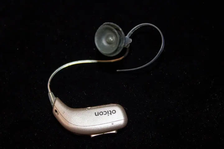 Slušni aparat koji se nosi iza uha, na tamnoj podlozi